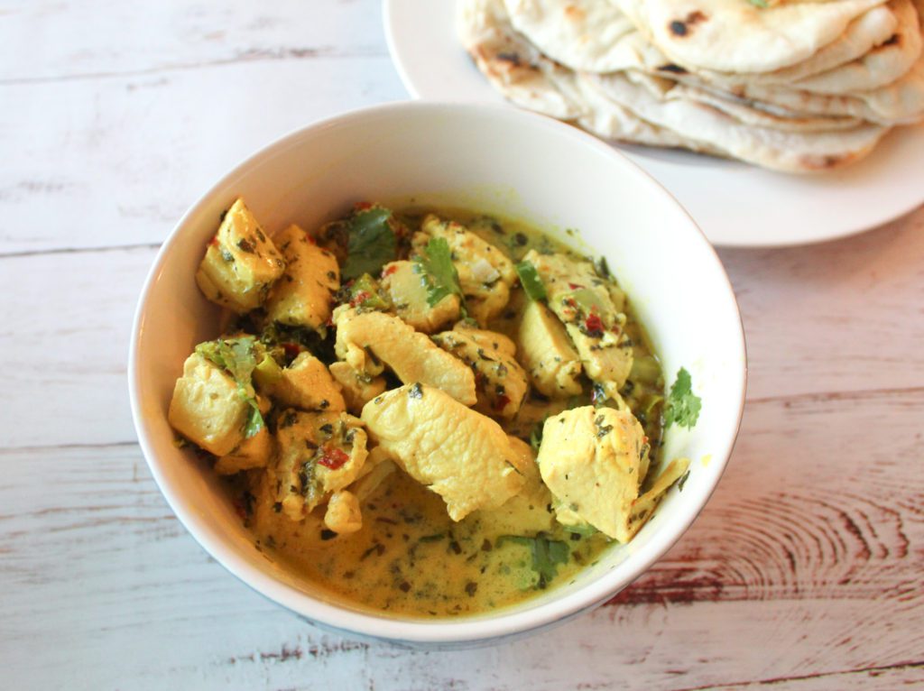 white chicken karahi in bowl, with naan in the background