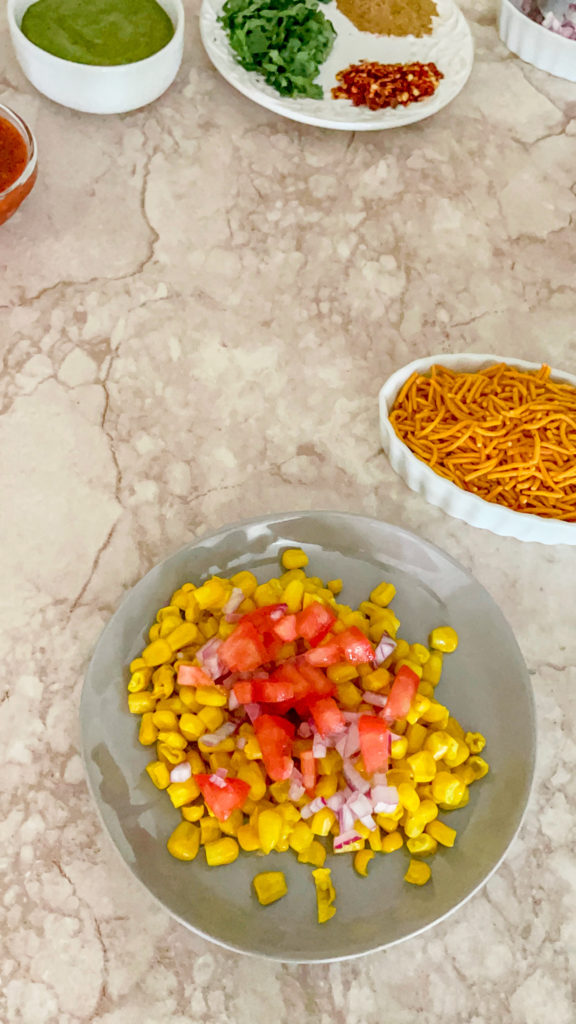corn, onions and tomatoes on a plate for corn chaat