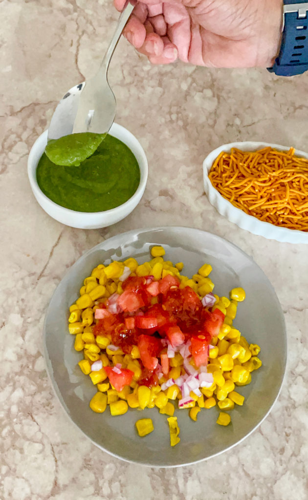 corn, onions and tomatoes on a plate for corn chaat