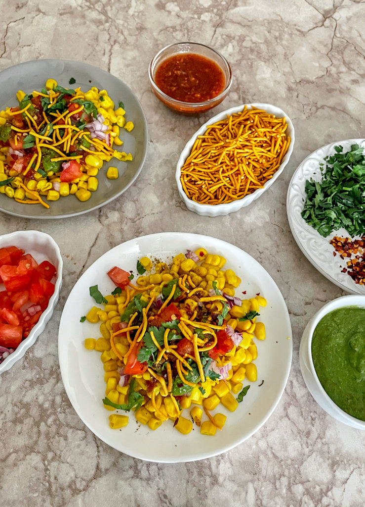 corn chaat on a plate with toppings on the side