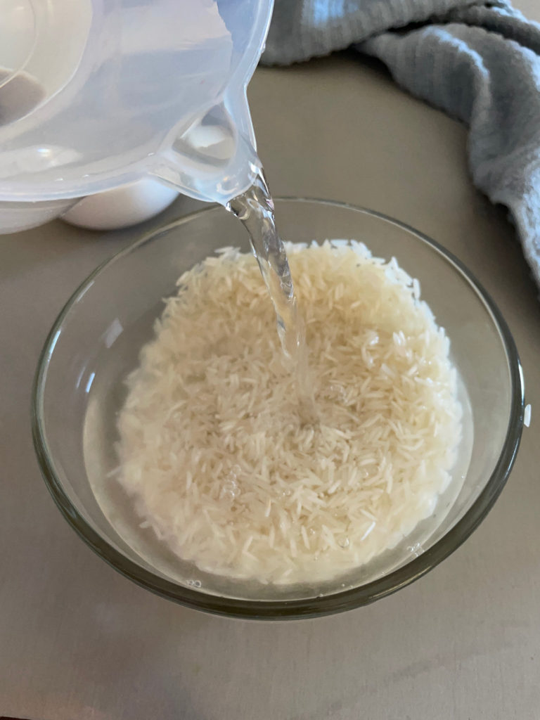 pouring water over basmati rice in a bowl for rajma chawal