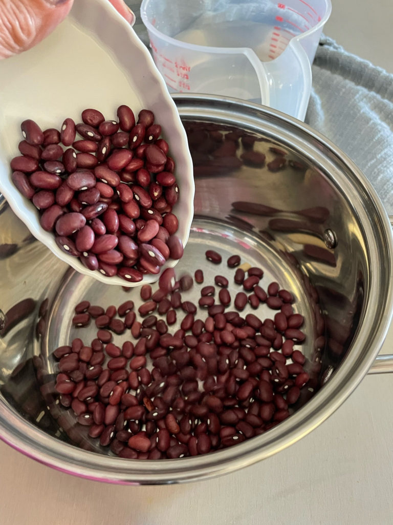 adding dried red kidney beans to a pot for rajma chawal