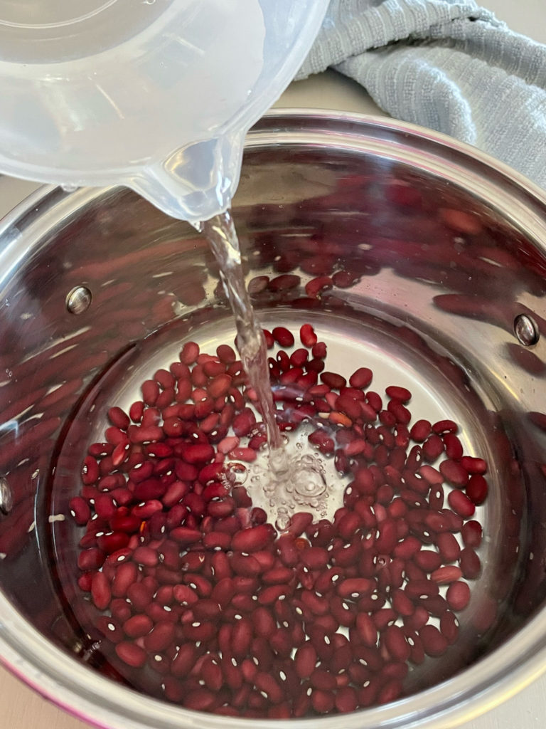 adding water to dried red kidney beans to a pot for rajma chawal