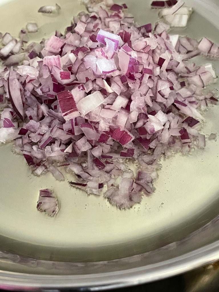 adding onions to a pot for rajma chawal