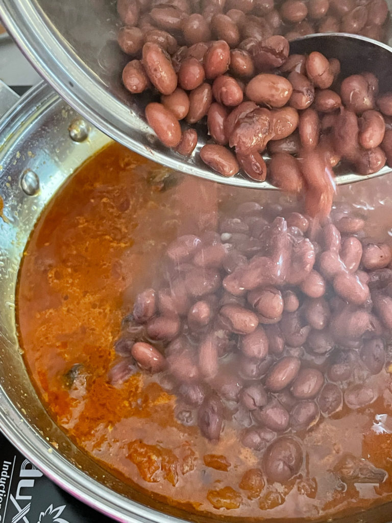 adding cooked red beans to the curry base for rajma curry