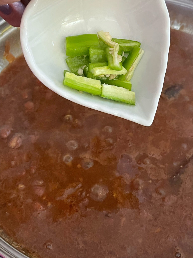 adding green chili to the rajma curry