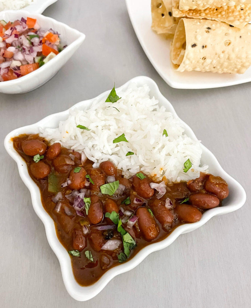 rajma chawal on a plate with rice garnished with onions and cilantro