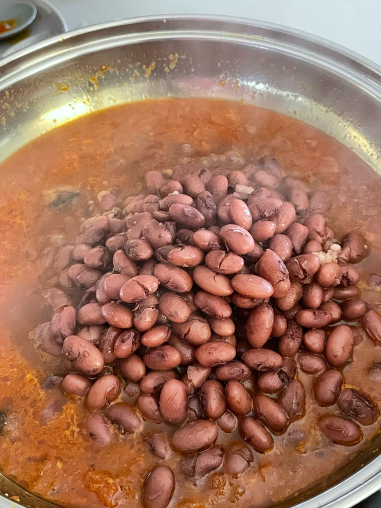 adding red beans to the curry base for rajma curry