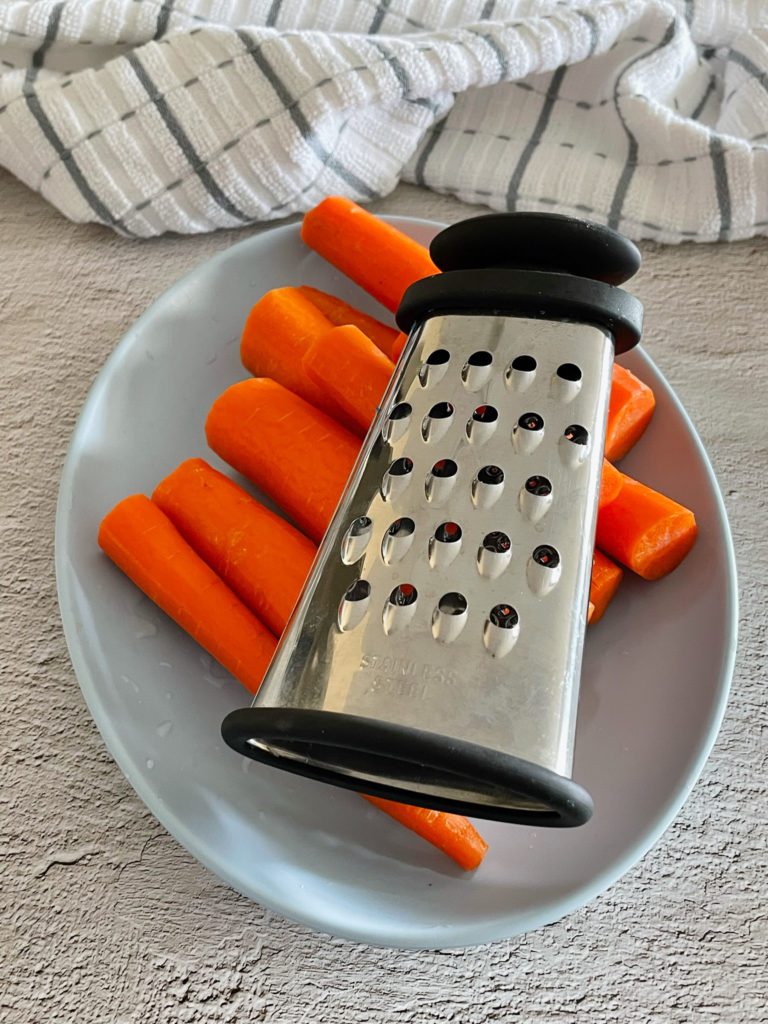carrots on a plate with a grater for gajar ka halwa