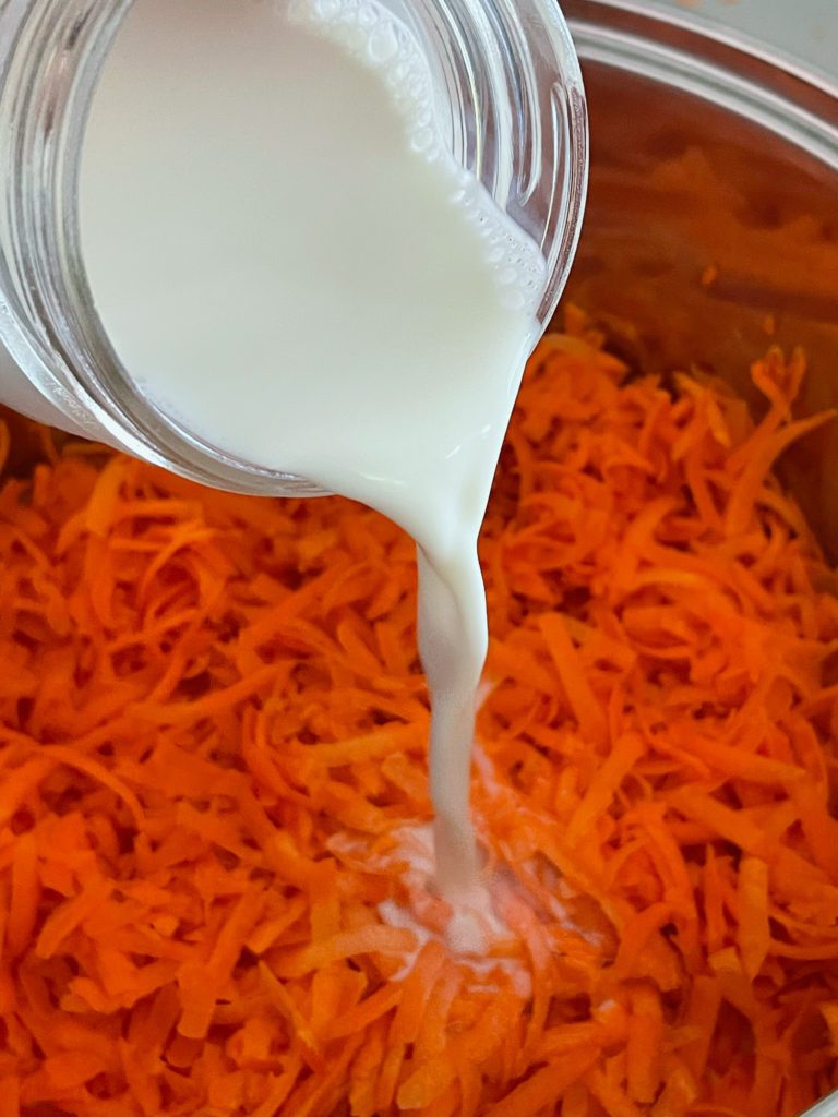 milk being poured onto carrots for gajar ka halwa