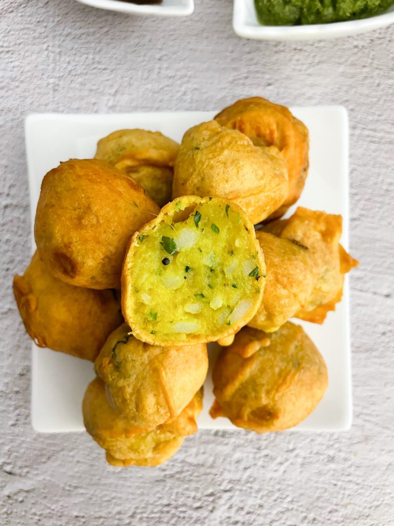 batata vada stacked on plate with top one cut in half