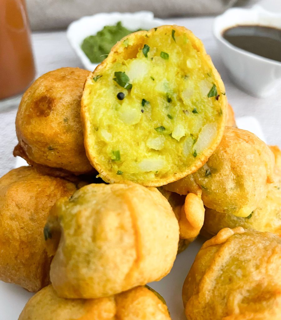 stack of batata vadas with bowl of imli chutney in background