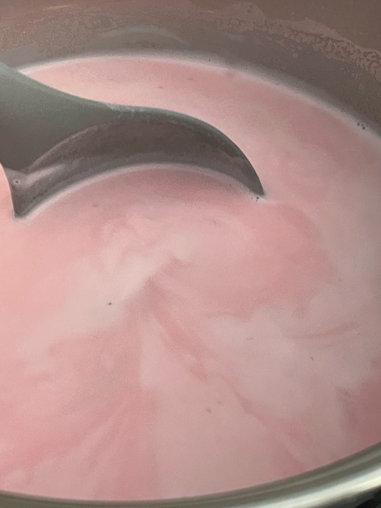 pink milk stirred with grey spoon