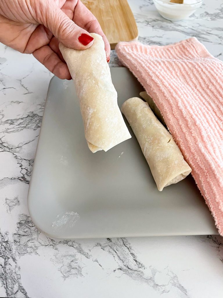 folded chicken egg roll transfers to plate with dish towel on top 