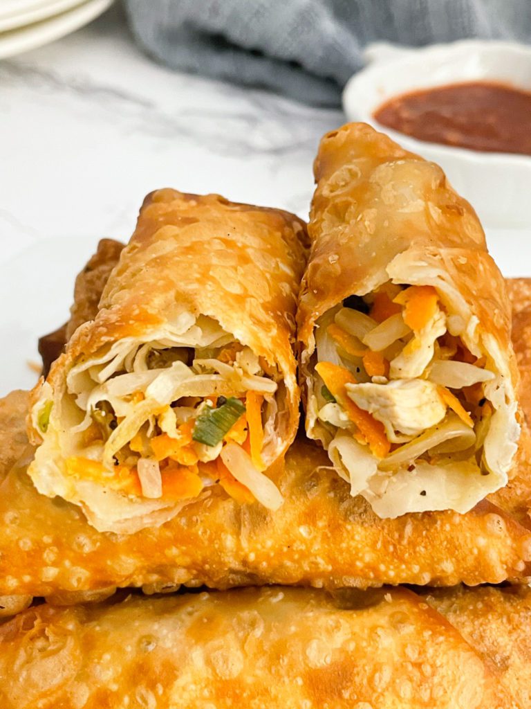 chicken egg rolls lined on plate, with top one cut in half