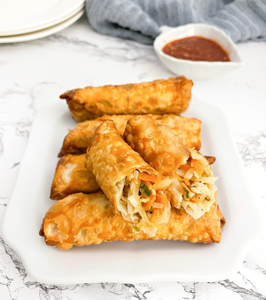 chicken egg rolls lined on plate, with top one cut in half